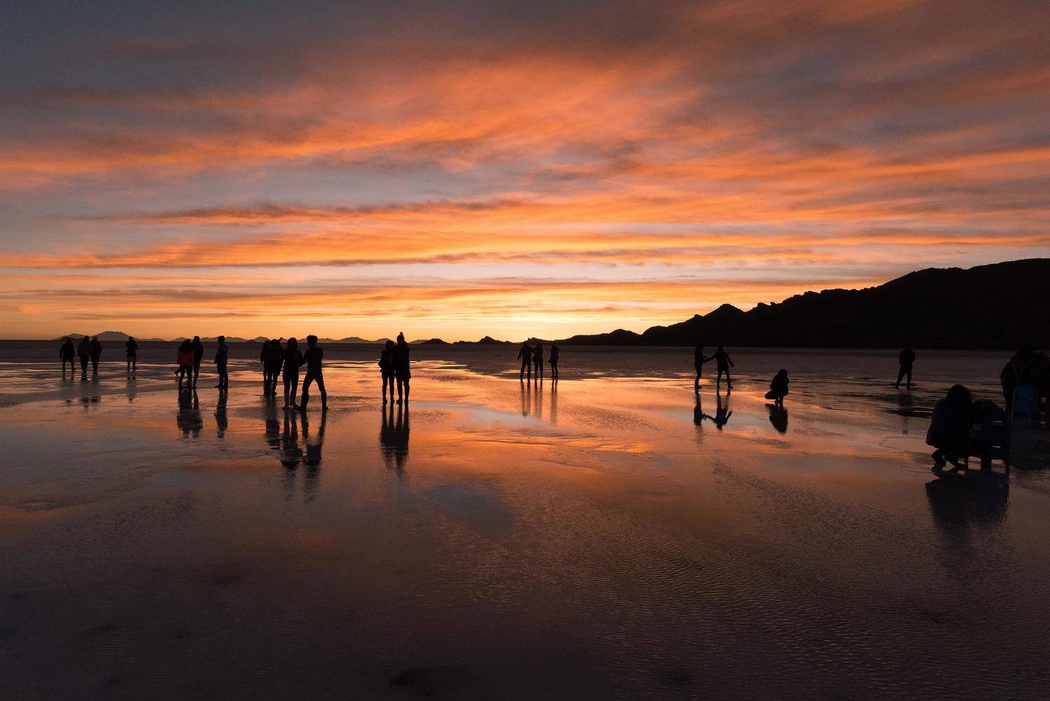 美しい夕暮れのウユニ塩湖と観光客のシルエット