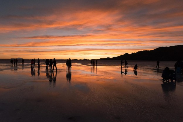 美しい夕暮れのウユニ塩湖と観光客のシルエット
